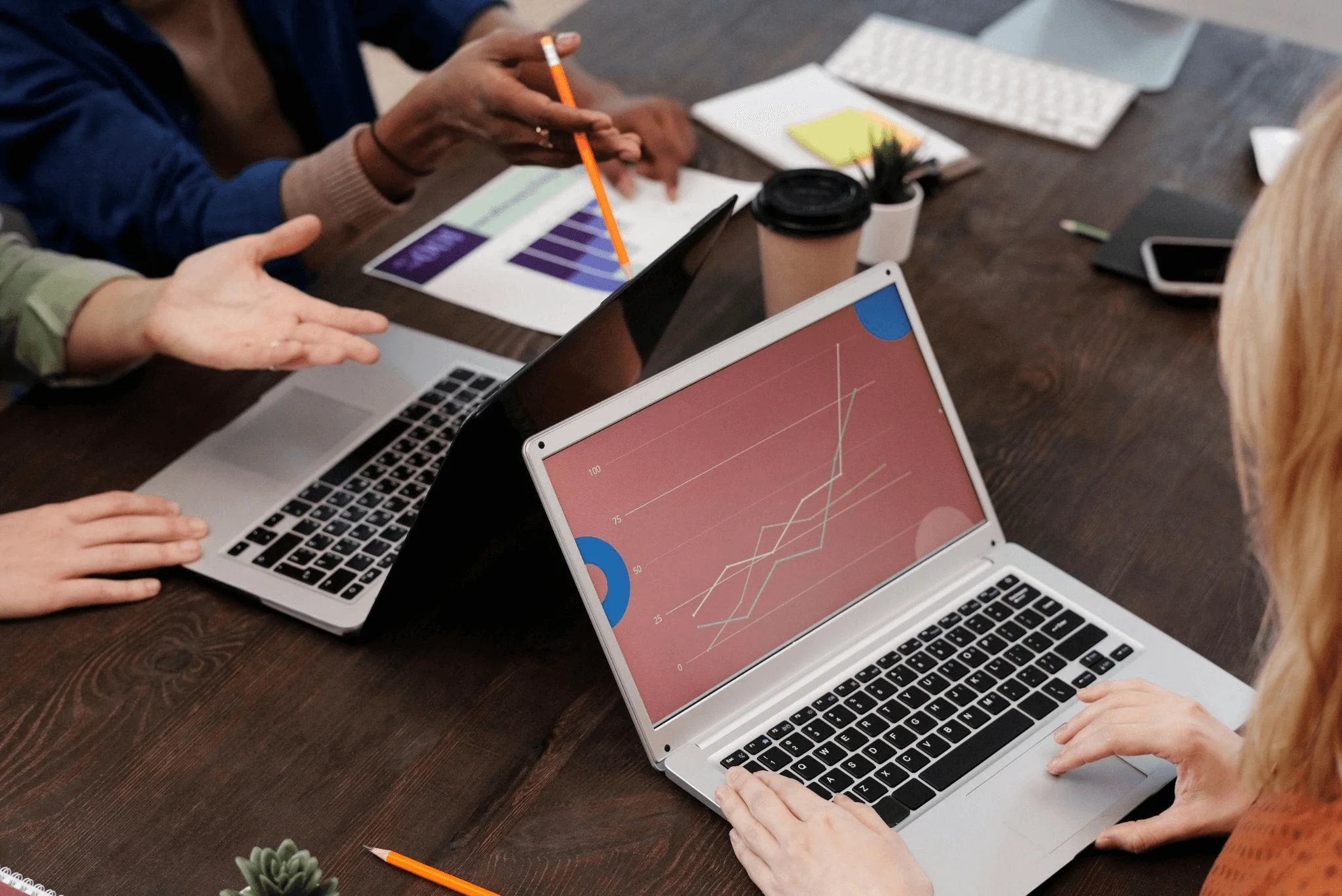 A group of people engaging with laptops around a table, representing teamwork and analysis of content marketing metrics to evaluate audience engagement.