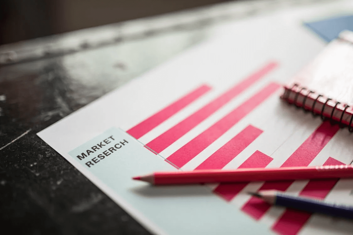 Market research document with red bar graphs and pencils, representing data-driven decisions for a business plan and market analysis.