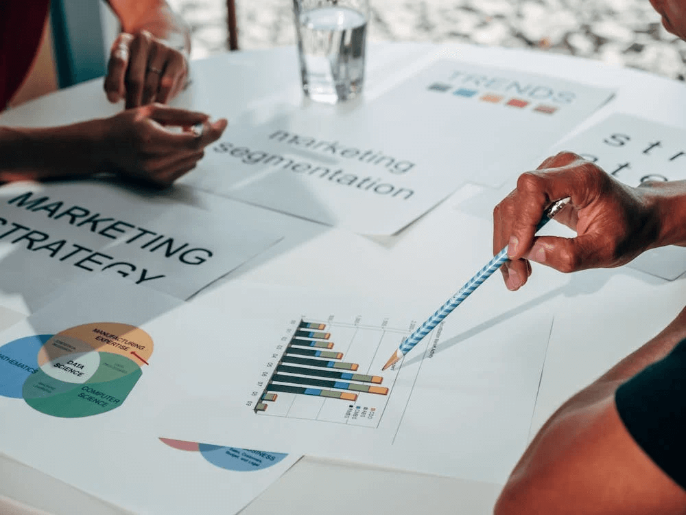 Close-up of a business meeting focusing on marketing strategy and segmentation, with charts and data analysis, illustrating the importance of market research in developing effective business plans.